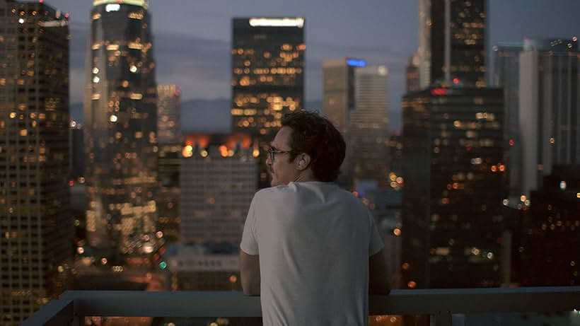 Joaquin Phoenix looking over a night city skyline